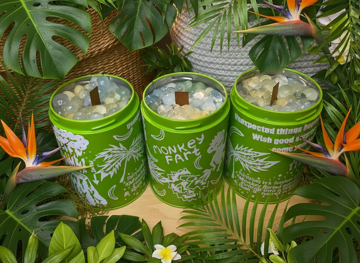 Three green candles with white text and designs, surrounded by tropical plants.